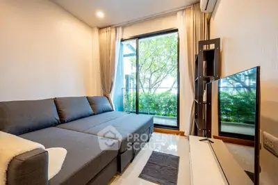 Modern living room with sleek gray sofa and large window overlooking lush greenery.