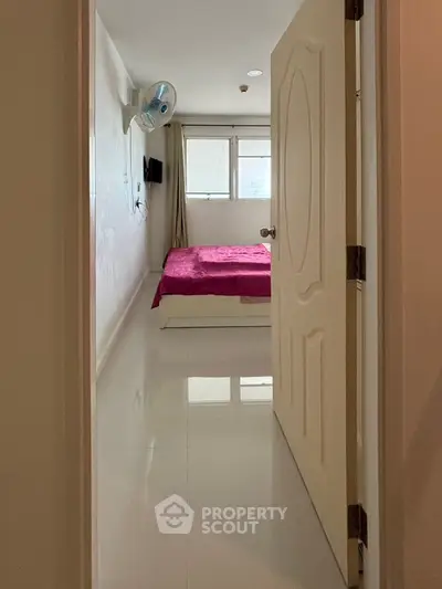 Cozy bedroom with pink bedding and wall-mounted fan, perfect for relaxation.