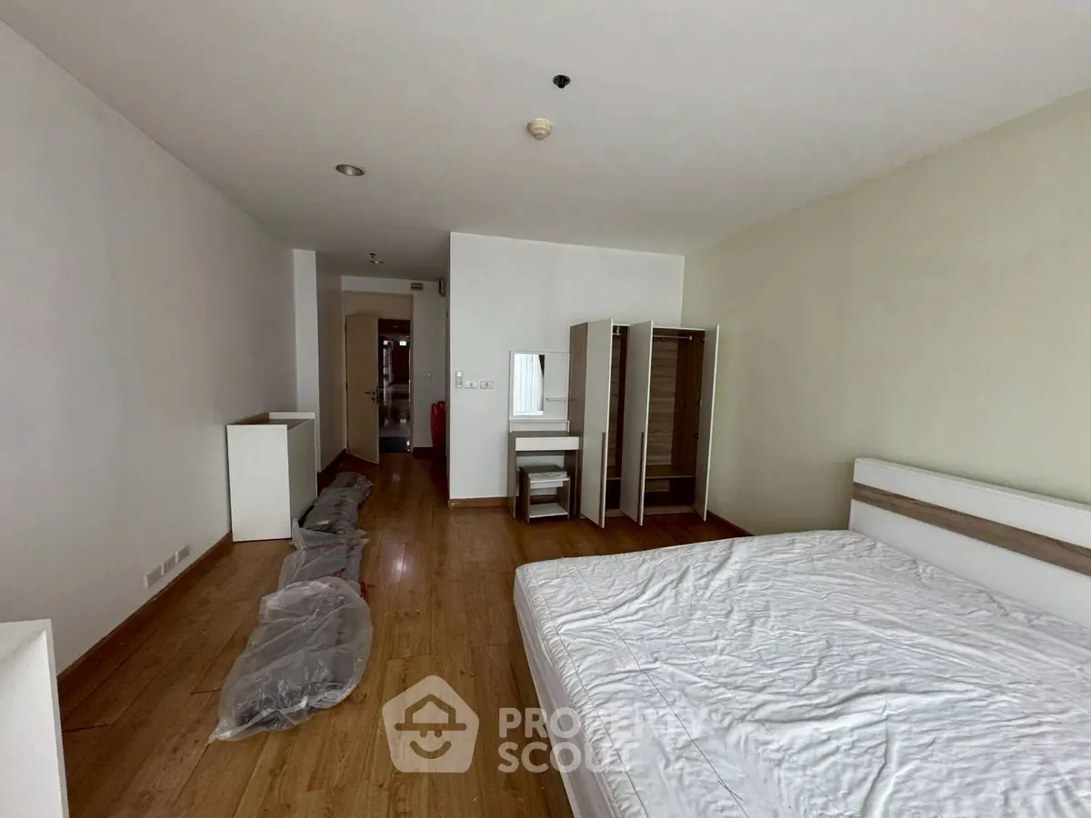 Spacious bedroom with wooden flooring and modern furniture in a minimalist design.