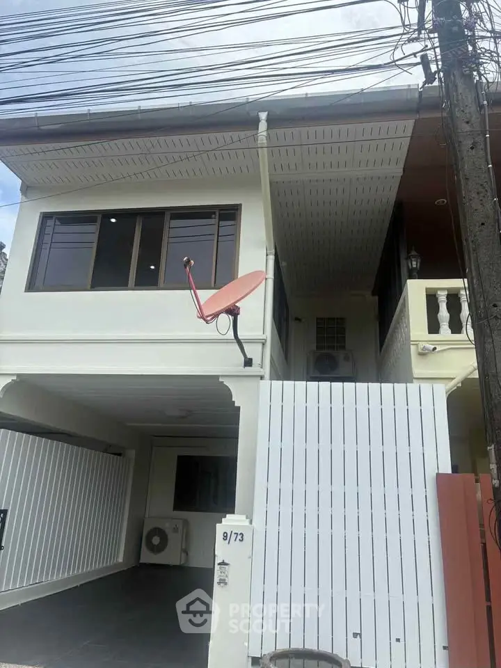 Charming two-story house with modern design and satellite dish in a quiet neighborhood.