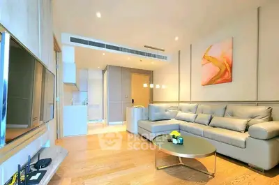 Modern living room with stylish decor and open kitchen layout, featuring a comfortable sofa and wall art.
