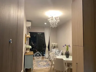 Elegant living room with chandelier and city view, featuring cozy dining area and stylish decor.