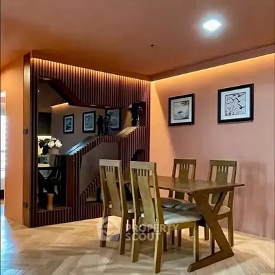 Modern dining area with wooden table and chairs, stylish wall decor, and warm lighting.