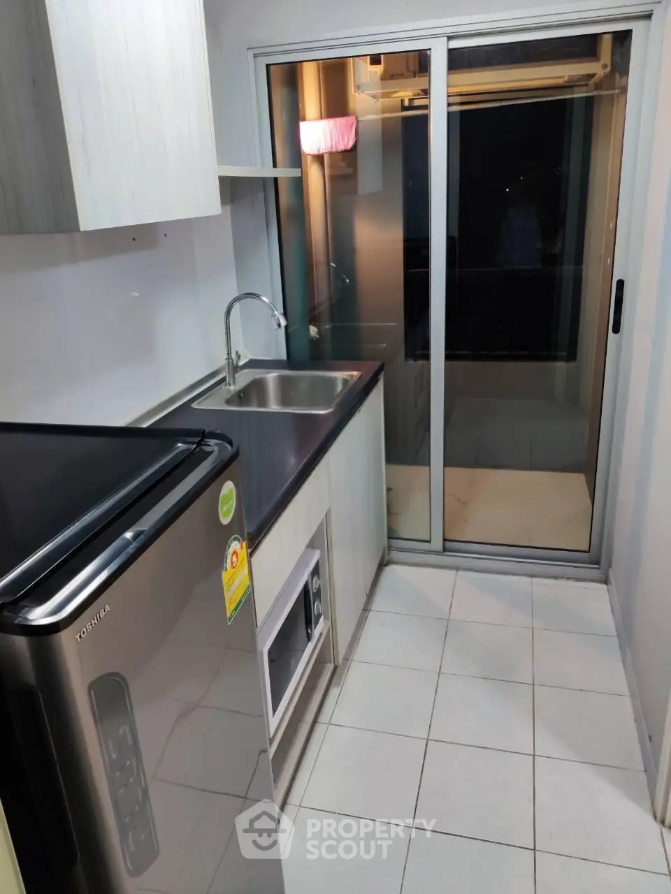 Modern kitchen with sleek appliances and sliding glass door leading to balcony.