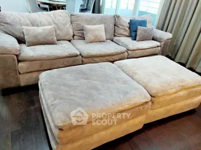 Spacious living room with plush beige sectional sofa and large ottomans, perfect for relaxation.