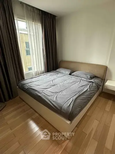 Cozy bedroom with wooden flooring and large window in modern apartment
