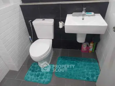 Modern bathroom with sleek fixtures and vibrant teal mats, perfect for a stylish home.