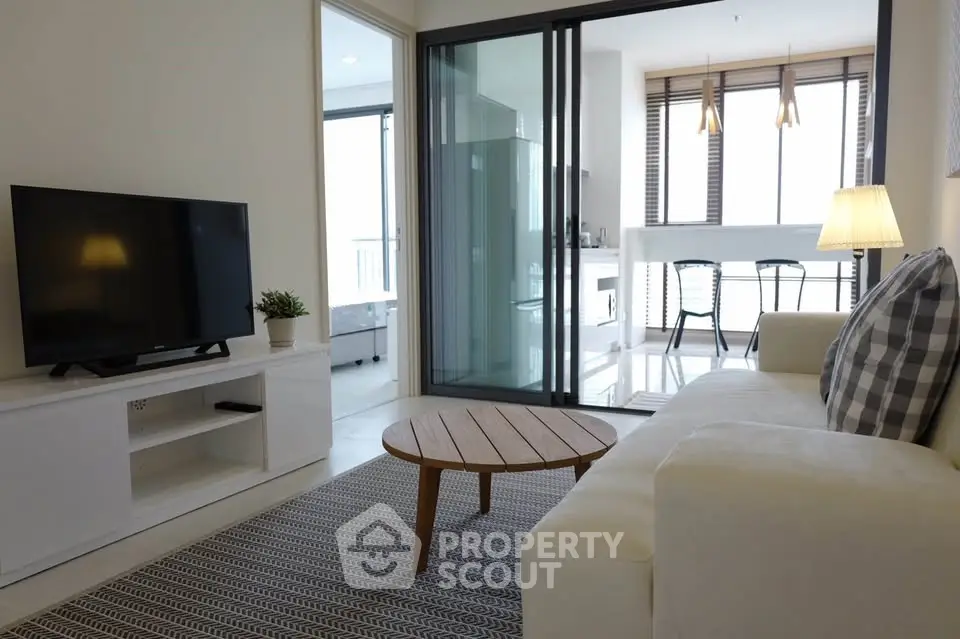 Modern living room with cozy sofa, TV, and open kitchen layout.