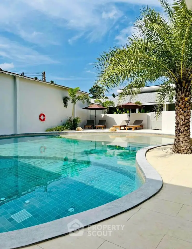Luxurious outdoor pool area with palm trees and sun loungers, perfect for relaxation and leisure.
