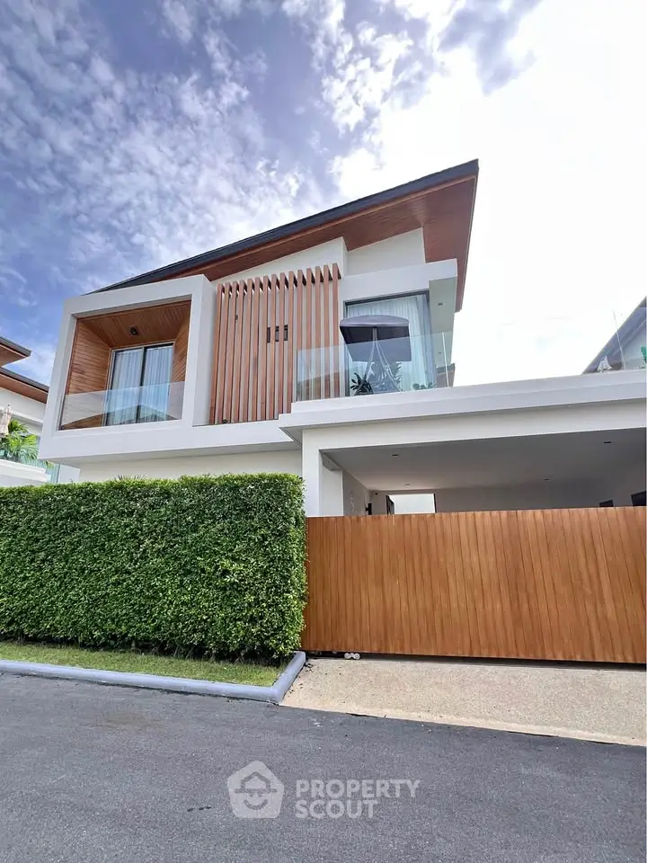 Modern luxury home with wooden accents and lush greenery under a clear blue sky.