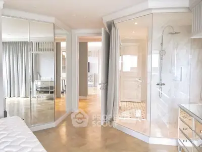 Luxurious bedroom with mirrored closets and elegant ensuite bathroom featuring glass shower.