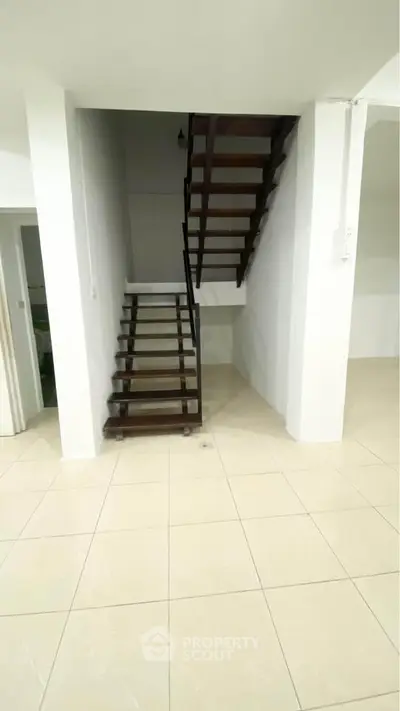 Modern staircase in a minimalist home interior with sleek wooden steps and white walls.