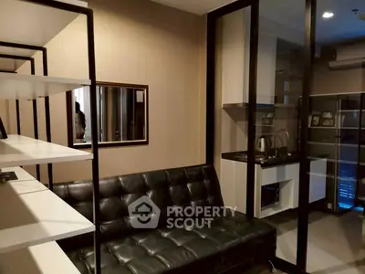 Modern living room with sleek black leather sofa and stylish open kitchen layout.