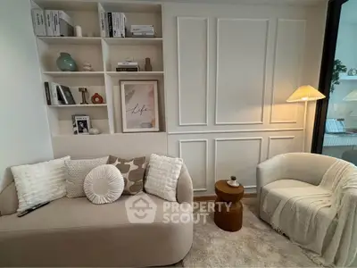 Cozy living room with elegant decor, featuring a plush sofa, stylish armchair, and decorative shelving.