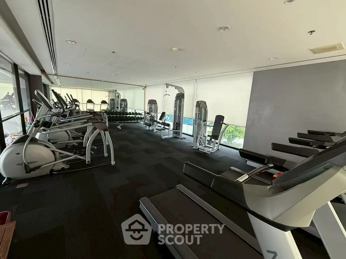 Spacious modern gym with state-of-the-art fitness equipment and large mirrors, ideal for an active lifestyle.