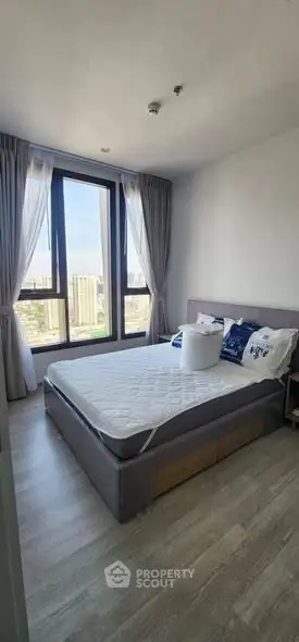 Modern bedroom with large window and city view, featuring stylish decor and natural light.