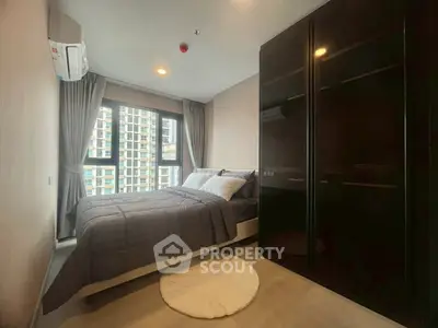 Cozy bedroom with modern furnishings and large window view in urban apartment.