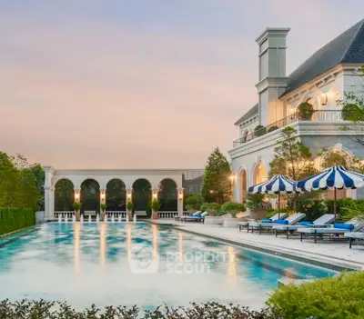 Luxurious estate with grand pool and elegant architecture at sunset.