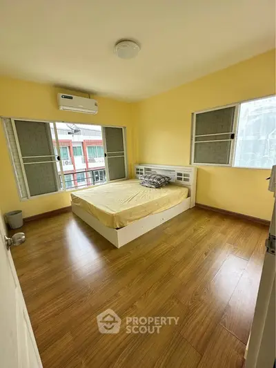 Bright bedroom with wooden flooring and large windows in modern apartment