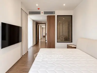Modern bedroom with sleek design, featuring a wall-mounted TV and elegant wooden accents.