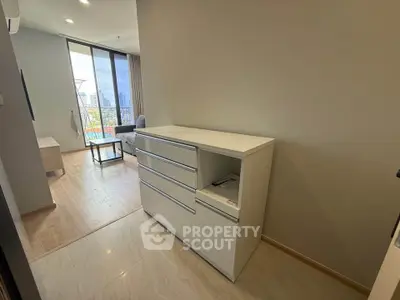 Modern apartment interior with sleek storage and city view from balcony.