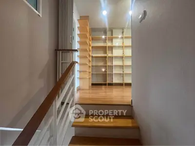 Modern interior with wooden staircase and built-in shelving unit, perfect for stylish storage solutions.