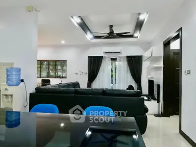 Modern living room with sleek black furniture and ceiling fan, open layout design.