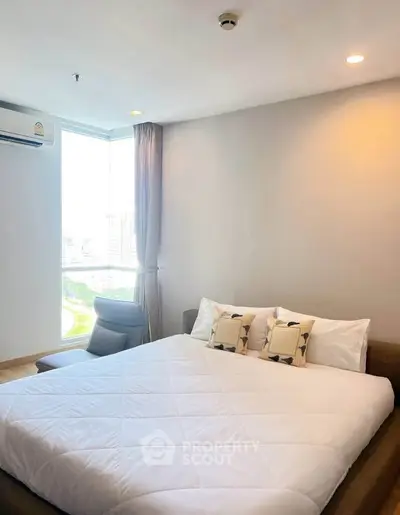 Modern bedroom with large window and city view, featuring a cozy bed and stylish decor.