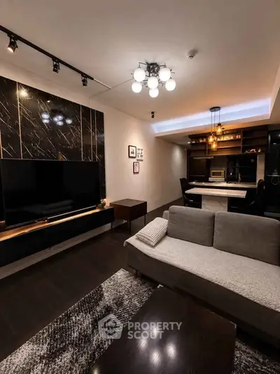 Modern living room with sleek design, featuring a large TV, stylish lighting, and a cozy seating area.