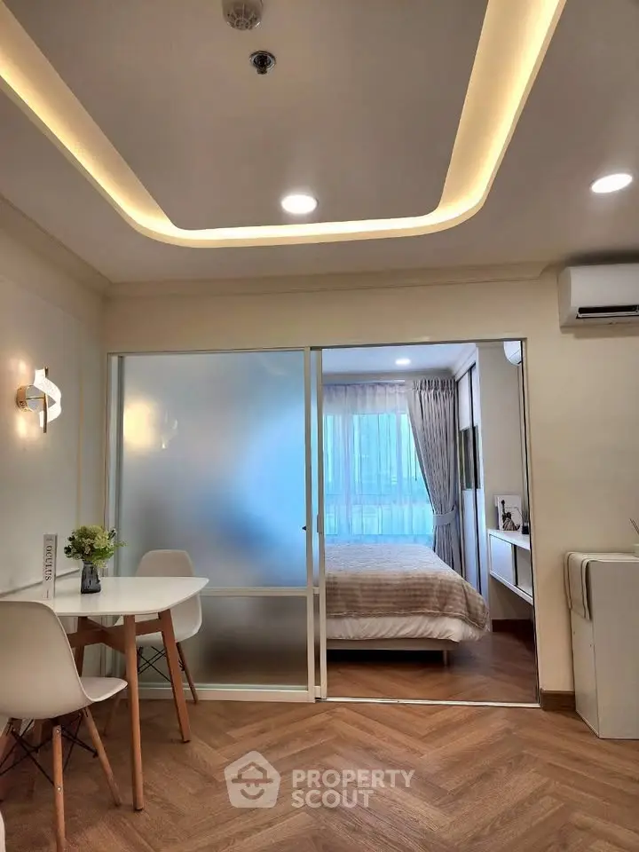Modern apartment interior with stylish bedroom and dining area, featuring elegant lighting and wooden flooring.