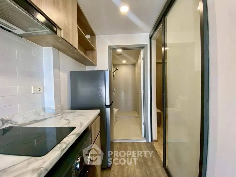 Modern kitchen with marble countertop and sleek appliances in compact apartment