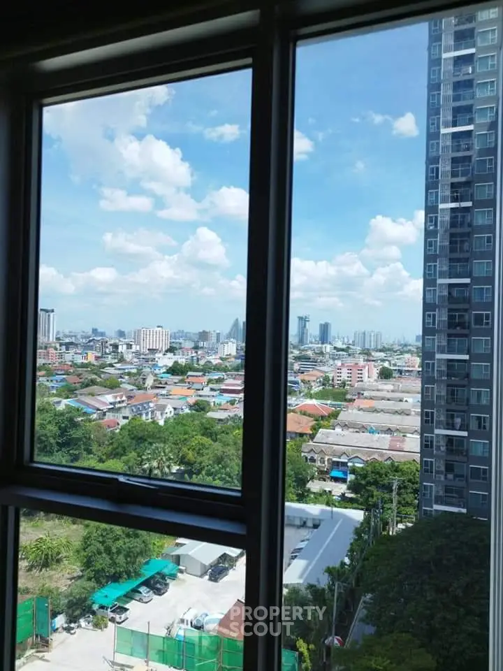 Stunning cityscape view from high-rise apartment window with clear blue sky.