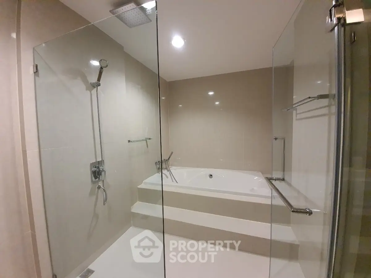 Luxurious bathroom with glass shower and modern bathtub in elegant real estate property.