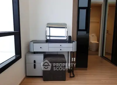 Modern bedroom with sleek vanity and ensuite bathroom in stylish apartment.