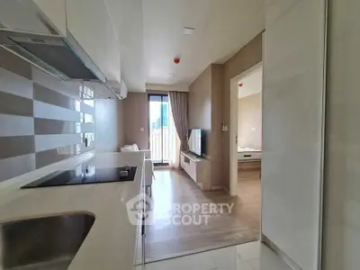 Modern apartment interior with open kitchen and living room leading to a balcony.