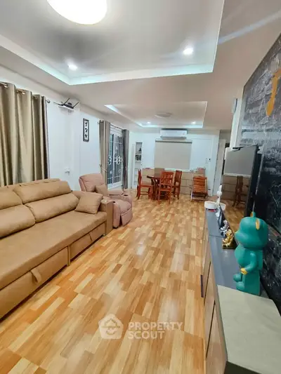 Spacious living room with modern decor and wooden flooring, featuring a cozy seating area and dining space.