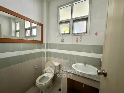 Modern bathroom with window, mirror, and granite countertop sink.