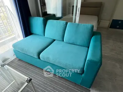 Modern living room with turquoise sofa and glass table in bright apartment.