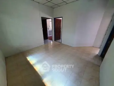 Spacious empty room with tiled floor and open doorways, perfect for customization.