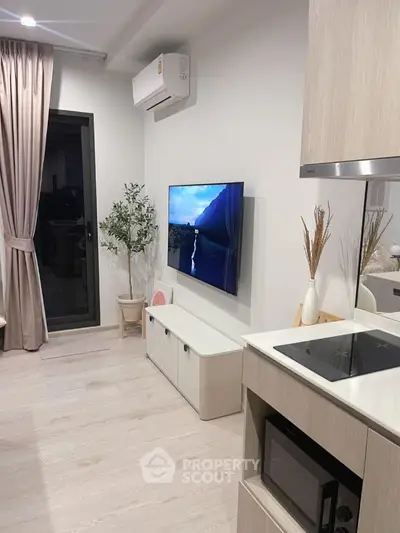 Modern living room with wall-mounted TV and sleek kitchen area