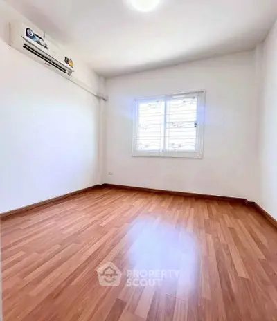 Spacious empty room with wooden flooring and air conditioning, perfect for customization.