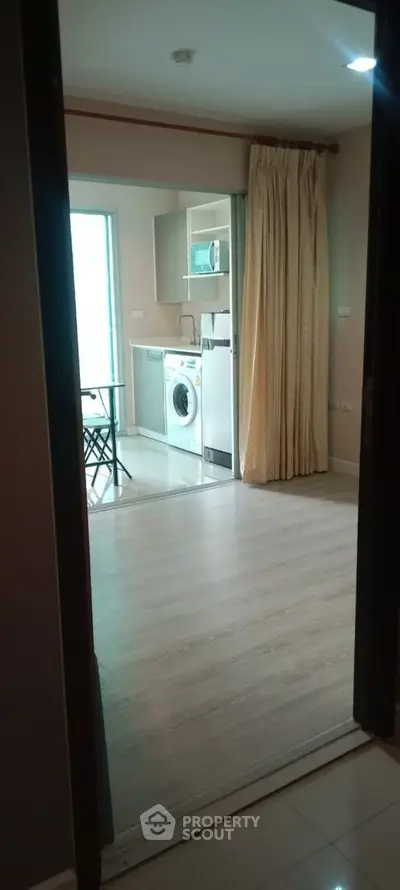 Modern apartment interior with washing machine and microwave in open layout kitchen.