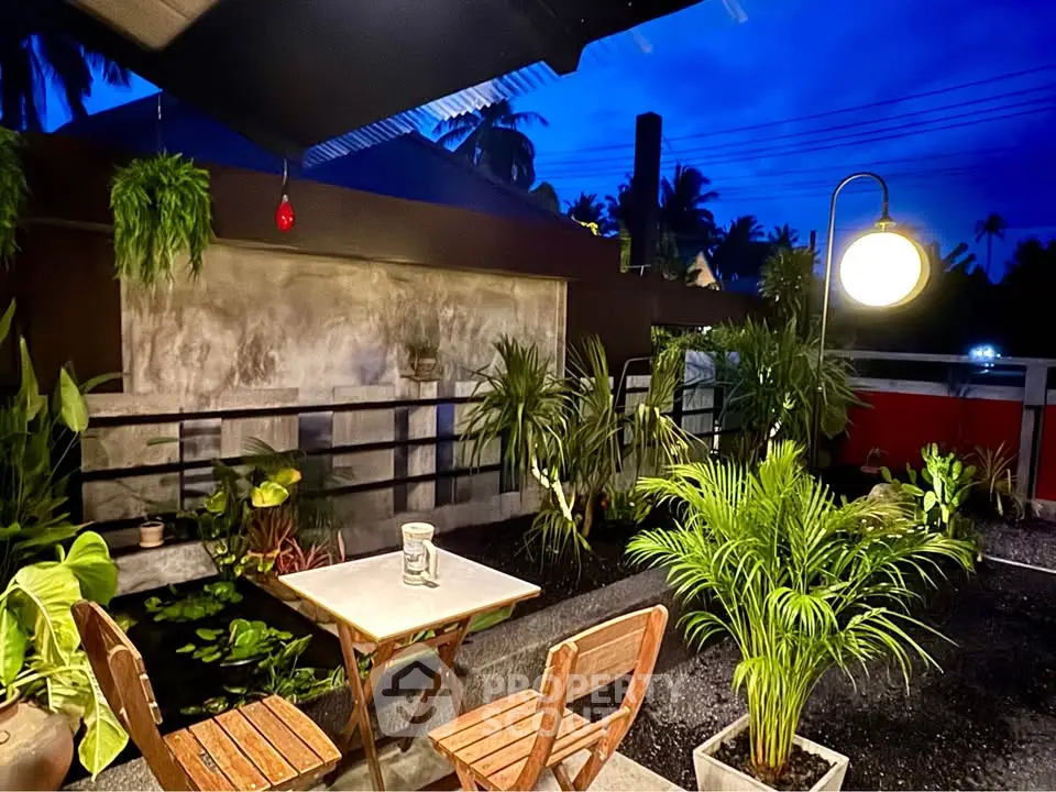 Charming outdoor patio with lush greenery and cozy seating, perfect for evening relaxation.
