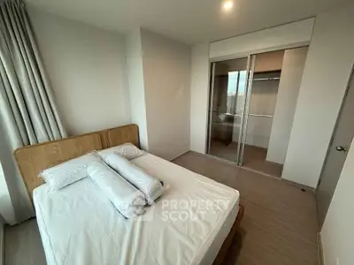 Modern bedroom with wooden flooring and mirrored closet doors in a bright apartment.