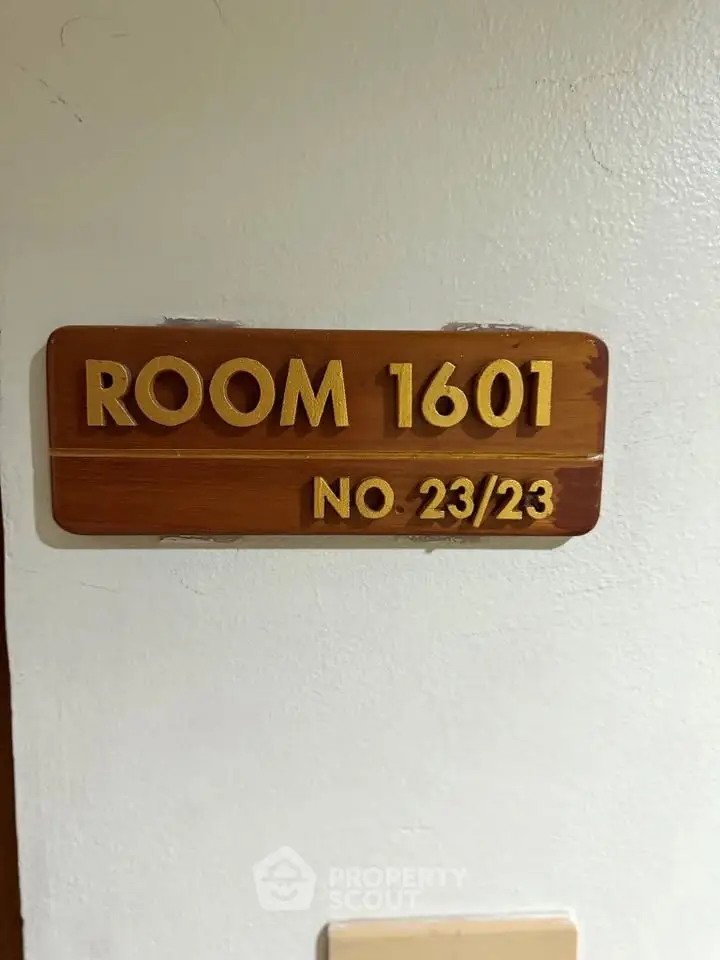 Room 1601 sign on a white wall indicating property unit number 23/23.