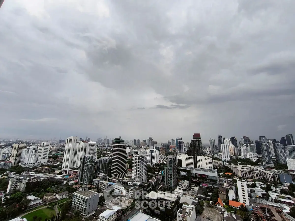 Stunning cityscape view from high-rise building showcasing urban skyline under cloudy sky.