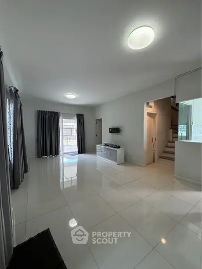 Spacious modern living room with sleek tile flooring and natural light, perfect for family gatherings.