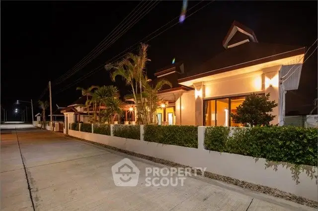 Stunning night view of modern villa with lush greenery and ambient lighting.