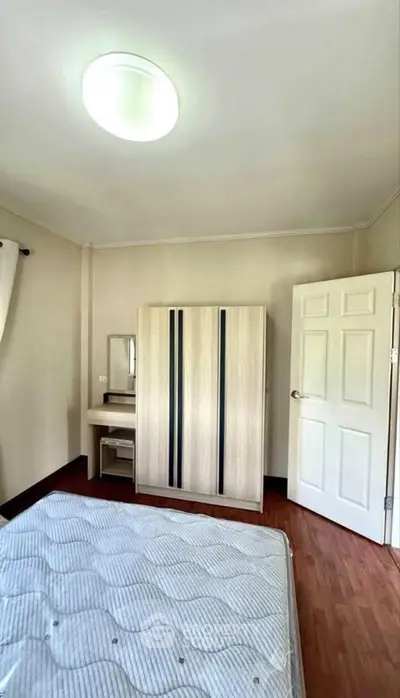 Cozy bedroom with wooden flooring and modern wardrobe, perfect for a comfortable living space.