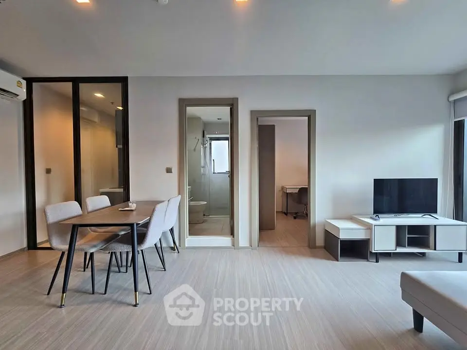 Modern living room with dining area and open layout, featuring sleek furniture and neutral tones.
